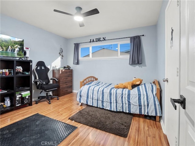 bedroom with ceiling fan, wood finished floors, and baseboards