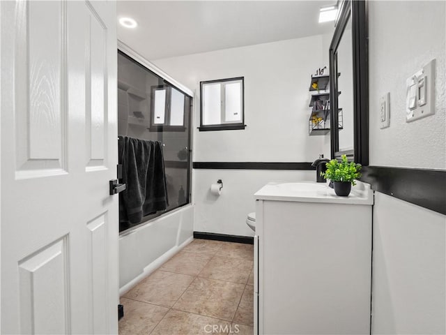 bathroom featuring enclosed tub / shower combo, tile patterned flooring, toilet, vanity, and baseboards