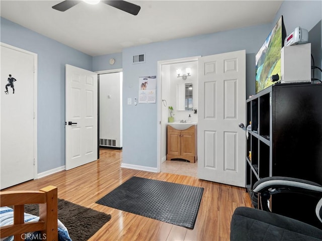 interior space featuring baseboards, light wood-style flooring, visible vents, and a sink