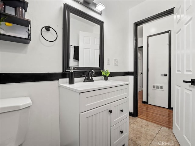 half bath featuring visible vents, vanity, toilet, and tile patterned floors