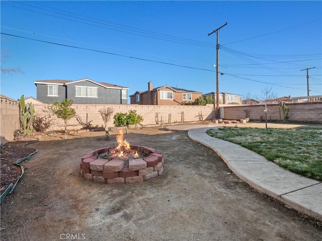 view of yard featuring a fire pit, a fenced backyard, and a residential view