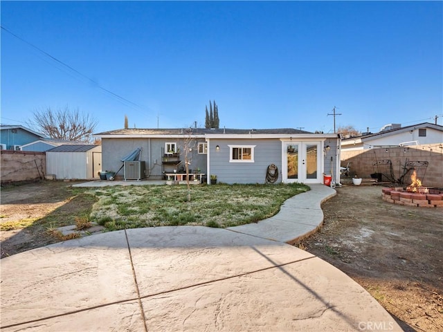 back of property featuring a patio, an outbuilding, french doors, a shed, and central AC