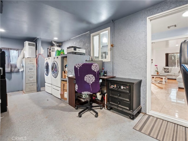 home office featuring water heater, visible vents, washer and dryer, and a textured wall