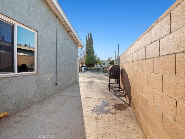 exterior space featuring a patio area, fence, and stucco siding