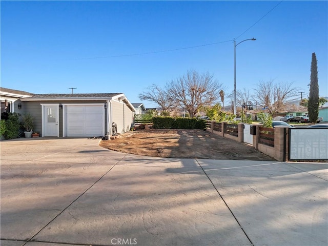 view of side of home with a garage, driveway, and fence