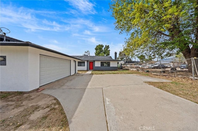 view of front of home with an attached garage, fence, concrete driveway, and stucco siding