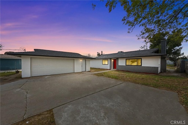 ranch-style house with a garage, brick siding, and stucco siding