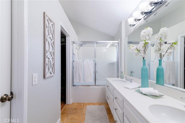 full bathroom with vaulted ceiling, bath / shower combo with glass door, double vanity, and a sink