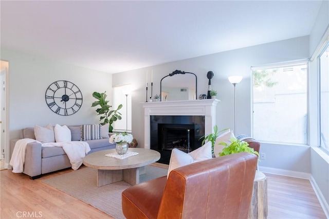 living area with light wood-style floors, baseboards, and a tile fireplace