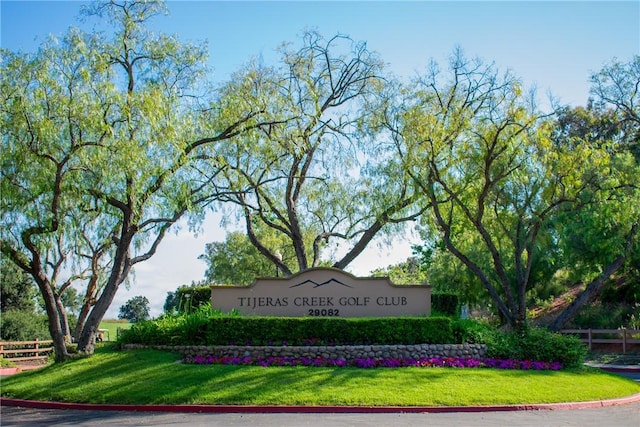 community / neighborhood sign with fence and a lawn