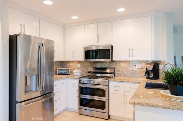 kitchen with white cabinets, decorative backsplash, stainless steel appliances, and a sink