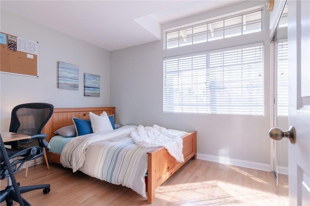 bedroom featuring multiple windows, baseboards, and wood finished floors