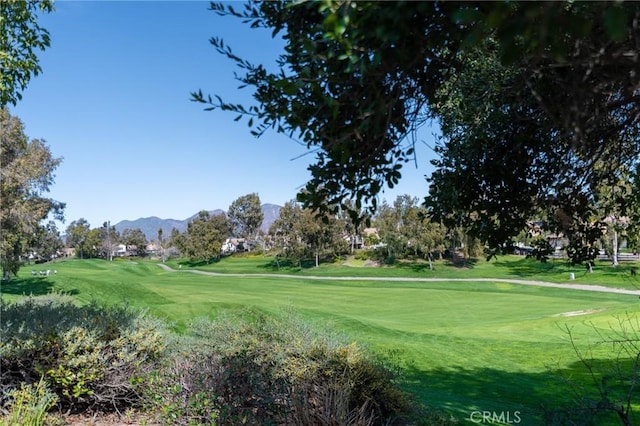 view of home's community with a yard, a mountain view, and golf course view