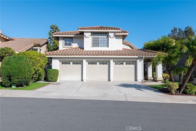 mediterranean / spanish house with a garage, a tile roof, driveway, and stucco siding