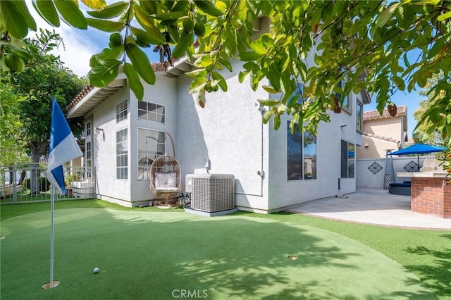 rear view of property with central AC, fence, exterior kitchen, stucco siding, and a patio area