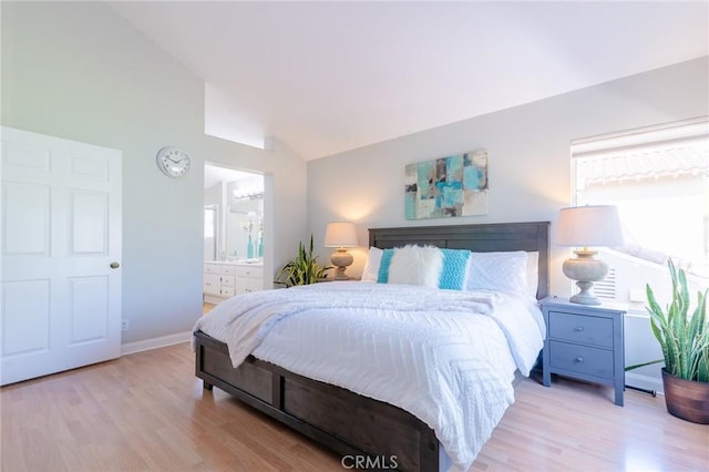 bedroom featuring baseboards, vaulted ceiling, ensuite bath, and light wood finished floors