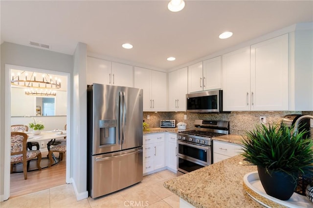 kitchen featuring visible vents, white cabinets, decorative backsplash, light stone counters, and stainless steel appliances