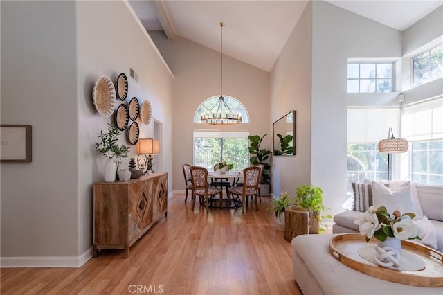 living area with light wood-style floors, a chandelier, visible vents, and high vaulted ceiling