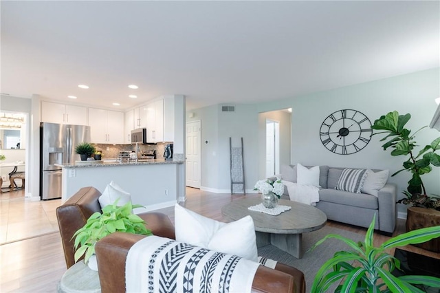 living area with light wood finished floors, baseboards, visible vents, and recessed lighting