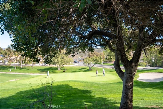 view of home's community featuring view of golf course and a lawn