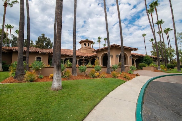 view of front of home featuring stucco siding, a tile roof, and a front yard