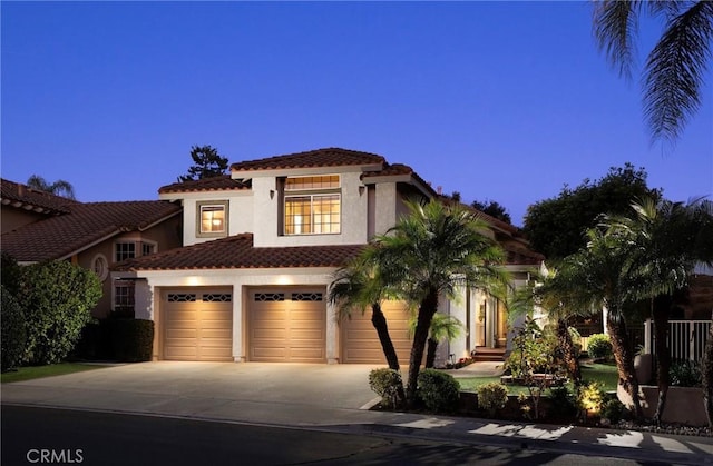 mediterranean / spanish-style home featuring driveway, a tile roof, and stucco siding