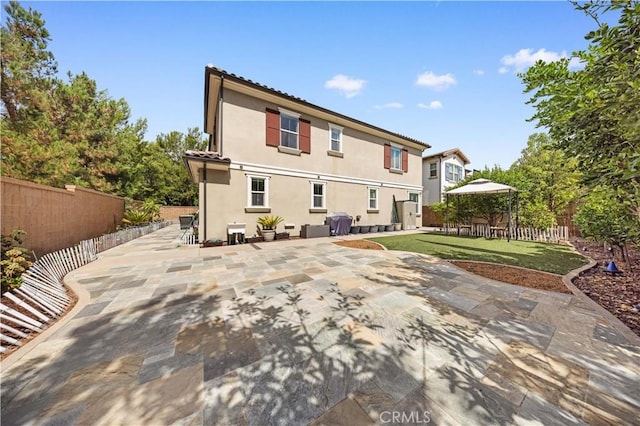 rear view of house with a patio area, a fenced backyard, a yard, and stucco siding