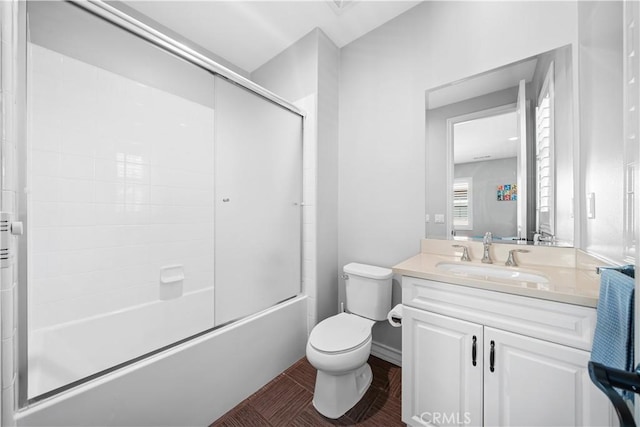 full bath with vanity, toilet, and bath / shower combo with glass door