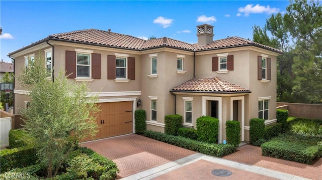 mediterranean / spanish-style house featuring decorative driveway, a tile roof, and stucco siding