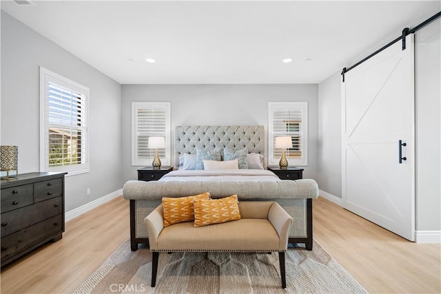 bedroom featuring light wood-type flooring, recessed lighting, baseboards, and a barn door