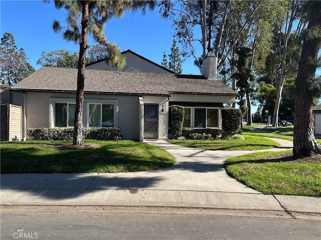 view of front of house with a front lawn, a chimney, and stucco siding