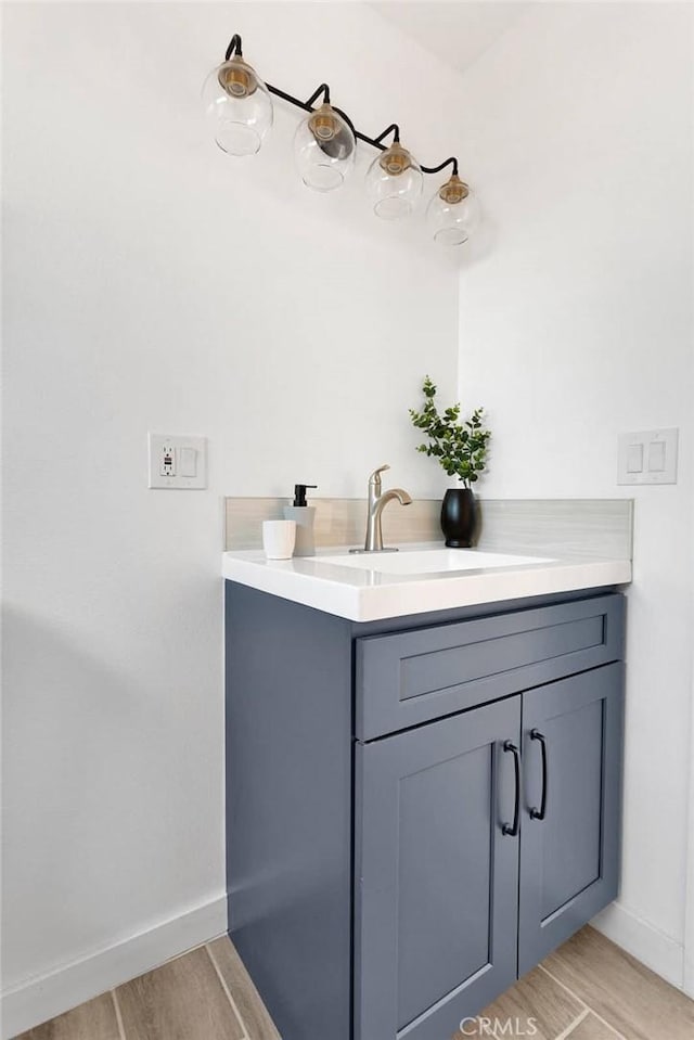 bathroom with wood finished floors, vanity, and baseboards