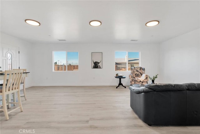 living room featuring light wood-type flooring, visible vents, and baseboards