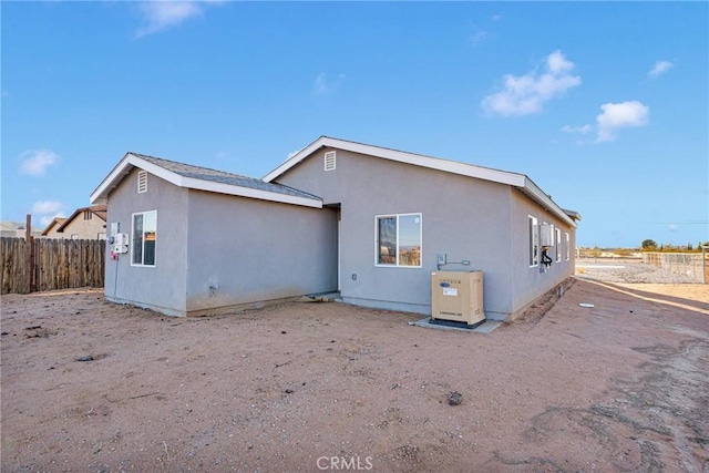 rear view of house featuring fence and stucco siding