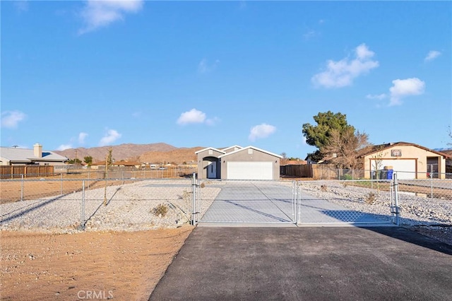 view of front of house with an attached garage, a gate, a mountain view, fence, and driveway