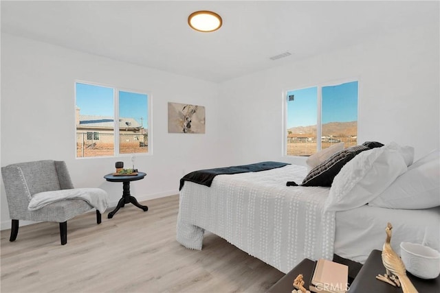 bedroom featuring light wood-style flooring, multiple windows, visible vents, and baseboards