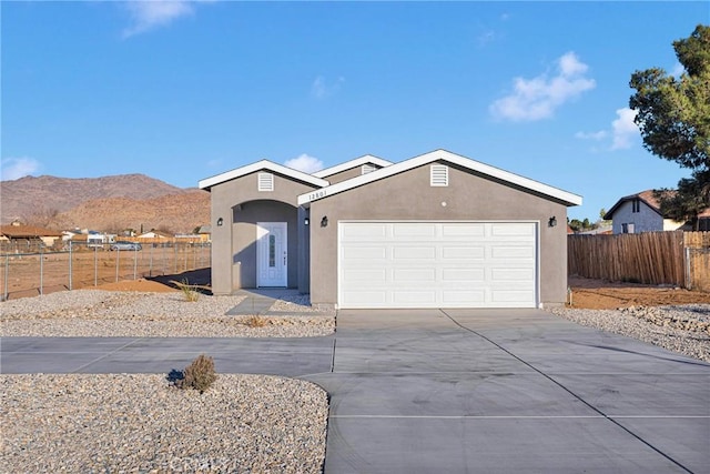 single story home with a mountain view, a garage, fence, concrete driveway, and stucco siding