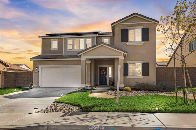 traditional-style house featuring a garage, solar panels, fence, driveway, and stucco siding