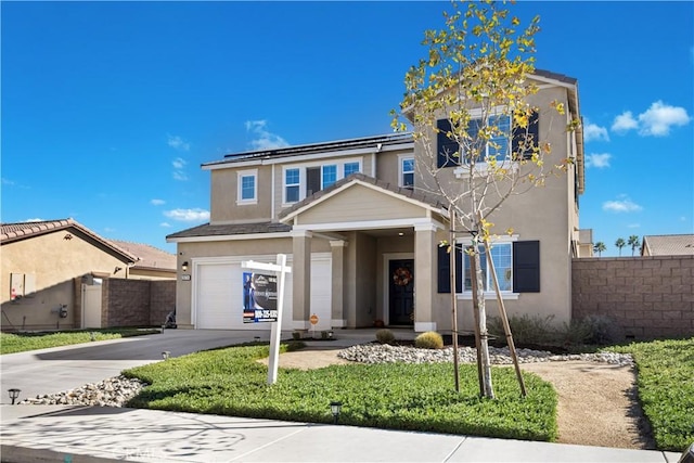 traditional-style house featuring driveway, an attached garage, fence, and stucco siding