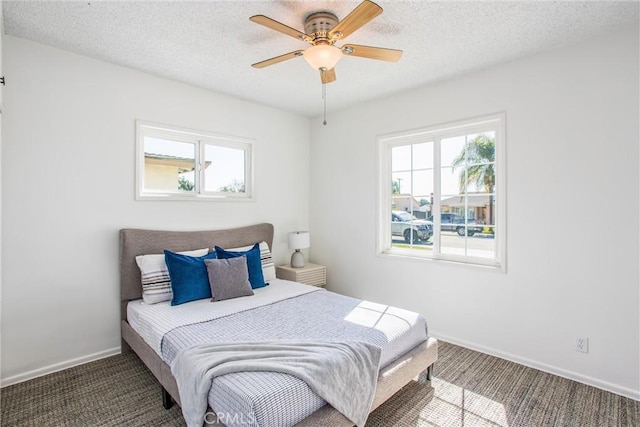 carpeted bedroom with multiple windows, ceiling fan, a textured ceiling, and baseboards