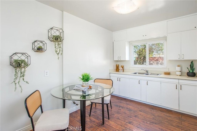 kitchen with dark wood-type flooring, a sink, baseboards, white cabinets, and light countertops