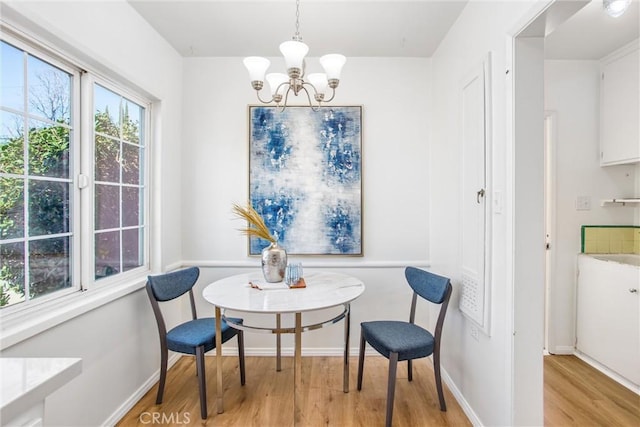 dining area with light wood finished floors, baseboards, and an inviting chandelier