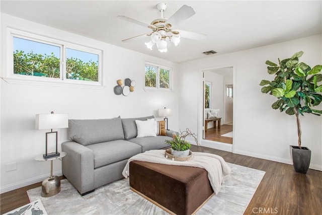 living area with visible vents, ceiling fan, baseboards, and wood finished floors