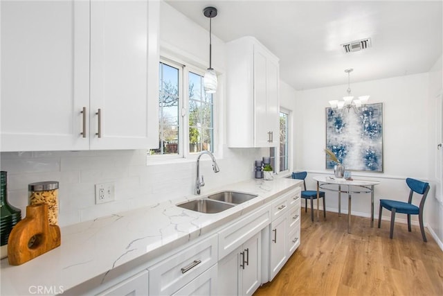 kitchen featuring hanging light fixtures, white cabinets, and a sink