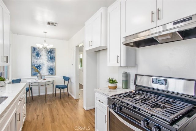 kitchen featuring visible vents, gas stove, white cabinets, light stone countertops, and under cabinet range hood