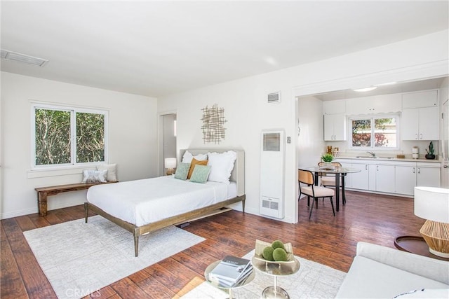 bedroom with dark wood-style floors, a sink, visible vents, and baseboards