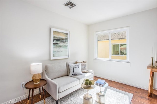 living area with visible vents, baseboards, and wood finished floors