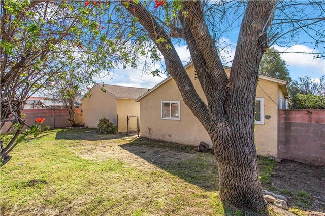 back of house featuring a yard, fence, and stucco siding