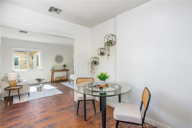 dining area featuring dark wood-style flooring, visible vents, and baseboards