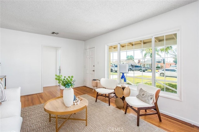 sitting room with light wood finished floors, plenty of natural light, visible vents, and a textured ceiling